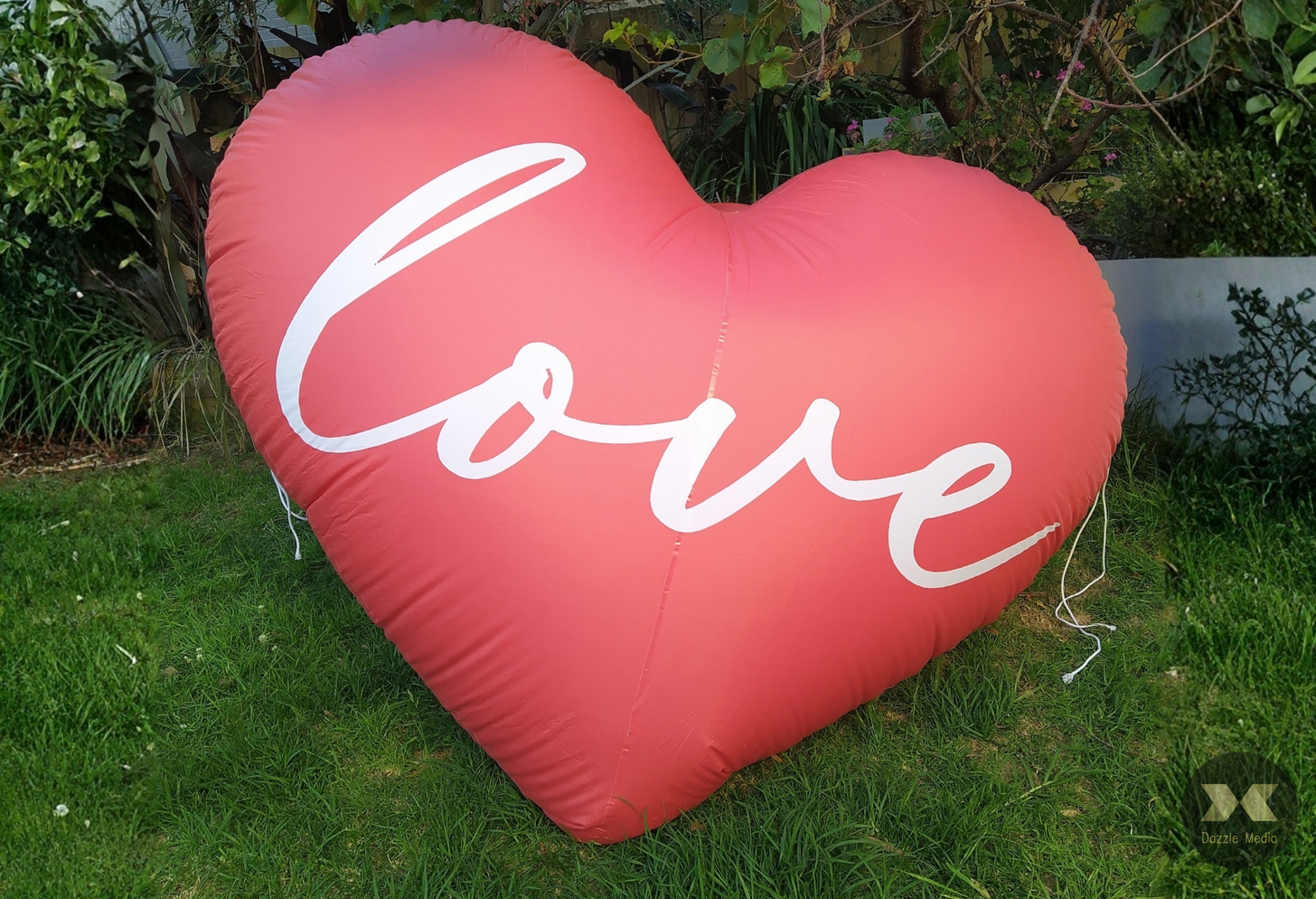 Oversized red inflatable heart balloon with white cursive Love script for outdoor lawn wedding and proposal hire in Melbourne